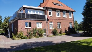 En tvåvåningsbyggnad med en fasad av tegel, flera fönster och en uppsättning solpaneler på taket.