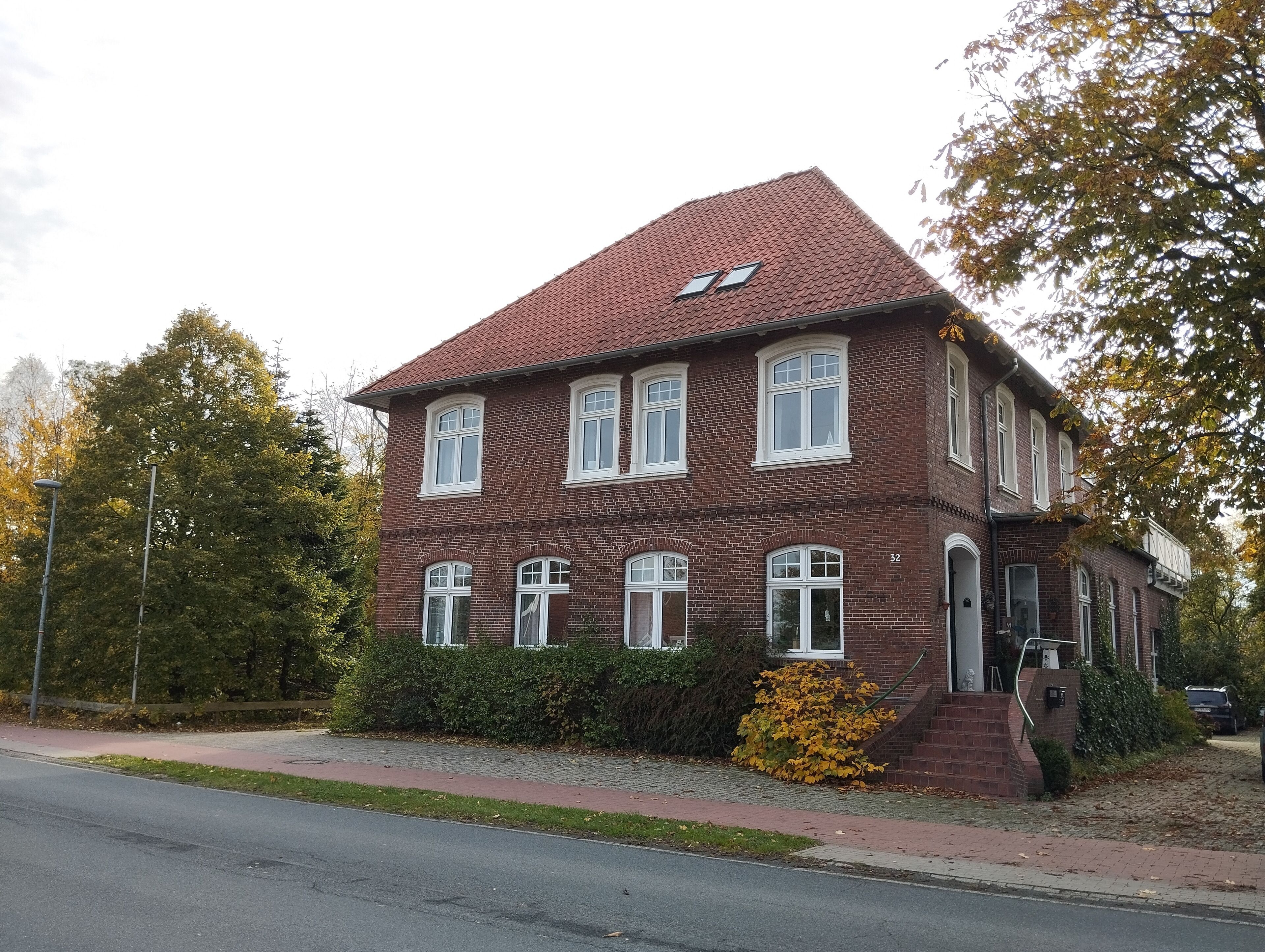 A two-story brick building with a red-tiled roof, multiple windows, and a small front porch.
