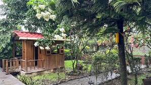 A wooden structure with a red roof, surrounded by lush greenery and a stone pathway. - Casa cómoda y tranquila a minutos de Xetulul (Guatemala)