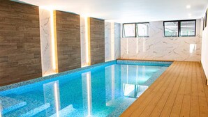 An indoor swimming pool with wooden flooring, marble walls, and tiled edges. - Cómodo apartamento a minutos de cayala (Guatemala City)