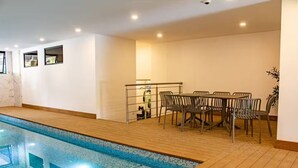 A swimming pool with a wooden deck, a table with chairs, and a small kitchenette area. - Cómodo apartamento a minutos de cayala (Guatemala City)