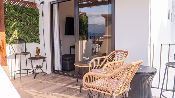 Eine Terrasse mit Korbstühlen, einem kleinen Tisch und einem Blumentopf.