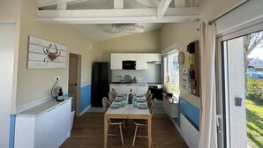 A compact kitchen with a dining area, featuring a wooden table and chairs, a refrigerator, and a microwave. - Villa les dunes (Merlimont)