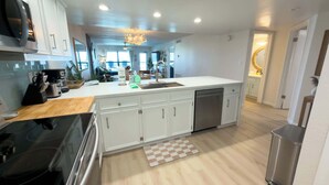 A modern kitchen with white cabinetry, a stainless steel dishwasher, and a wooden countertop. - Saida 3603 - 6 Floor Gulf-front Remodel - Sleeps 8 (South Padre Island)