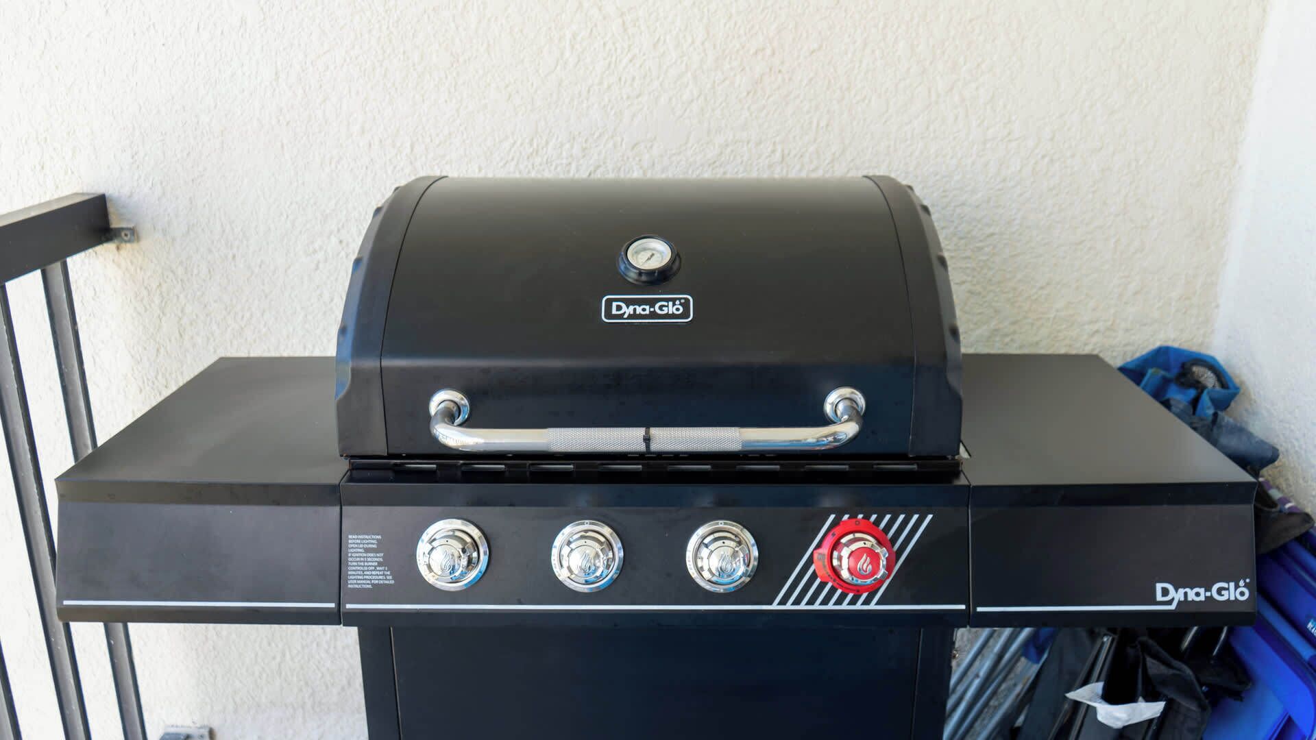 Una parrilla para exteriores negra con el nombre de marca 'Dyna-Gló' y cuatro perillas de control.