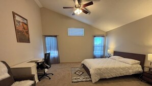 A bedroom with a bed, a desk, a chair, a ceiling fan, and two windows. - Calgary Home | 3BR Home | Sleeps 6 | Parking | 15min to Downtown (Calgary)
