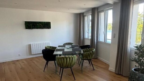 A dining area with a rectangular table, four chairs, a radiator, and a window with curtains.