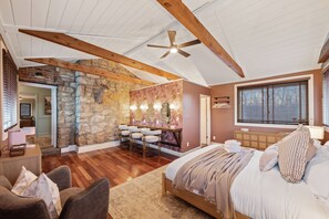 Ein Schlafzimmer mit einem großen Bett, einer Wand aus Stein, einem Schminktisch mit Beleuchtung und einem Deckenventilator.