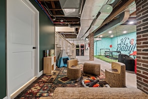 A hallway with a patterned carpet, wooden furniture, and a brick wall with a neon sign.