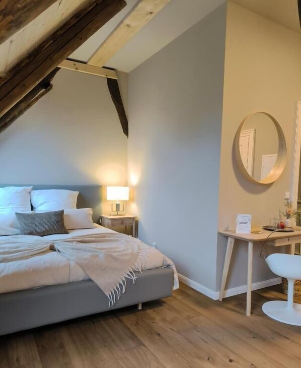 A bedroom with a bed, bedside table, lamp, and a desk with a chair. - Hotel Landhaus Plus Lüneburg (Lueneburg)
