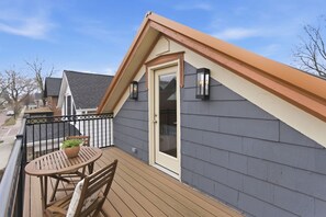 A residential deck with a table and chairs, a potted plant, and a door with a window.