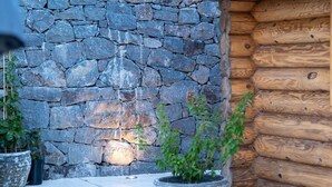 A stone wall with a wooden log cabin structure adjacent to it. - Cabin Tranquil Organic Heated Pool (La Solana)
