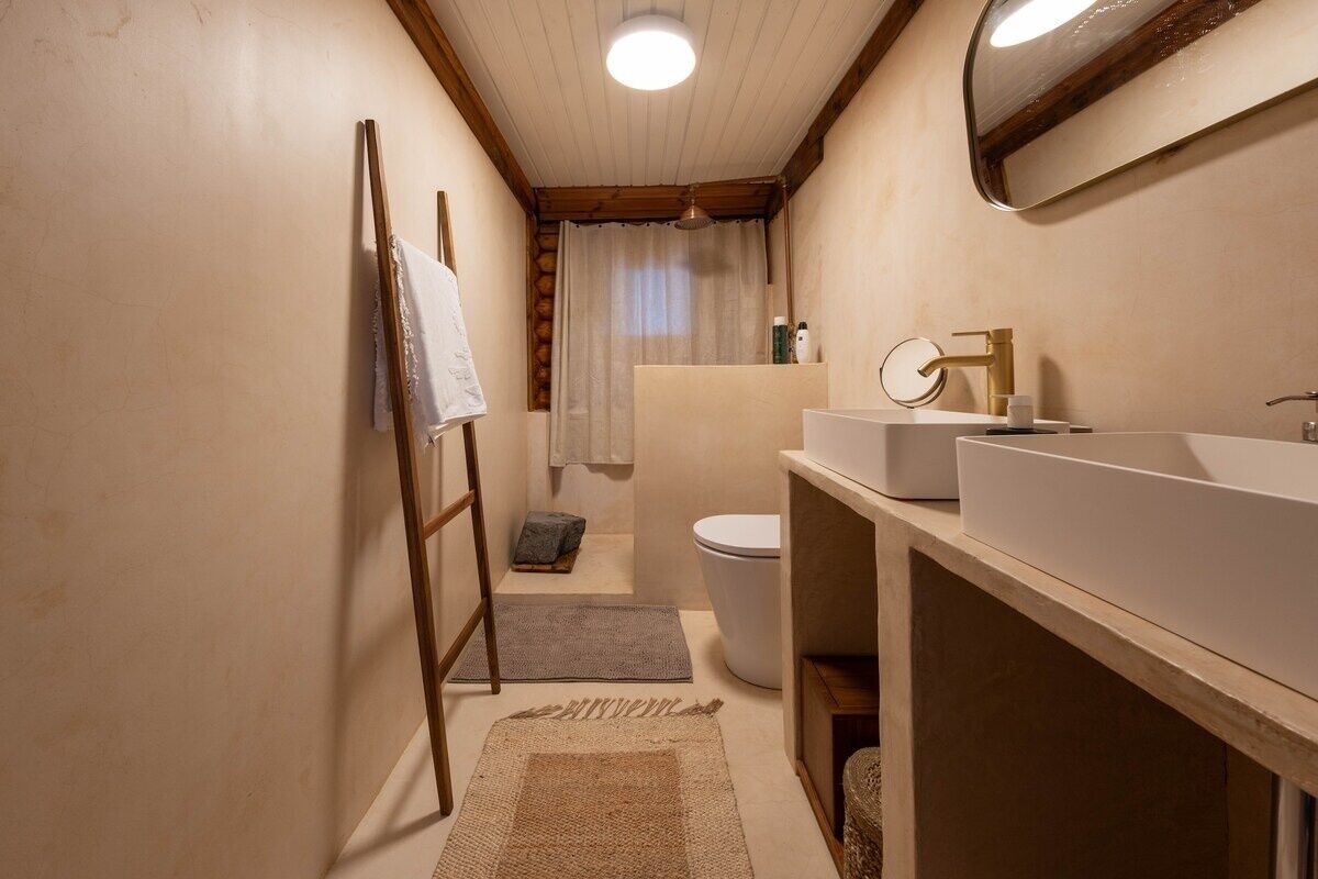 Een badkamer met een houten ladder, een witte wastafel, een toilet en een douchegordijn.