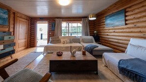 A log cabin interior with a sofa, coffee table, and a painting on the wall. - Cabin Tranquil Organic Heated Pool (La Solana)