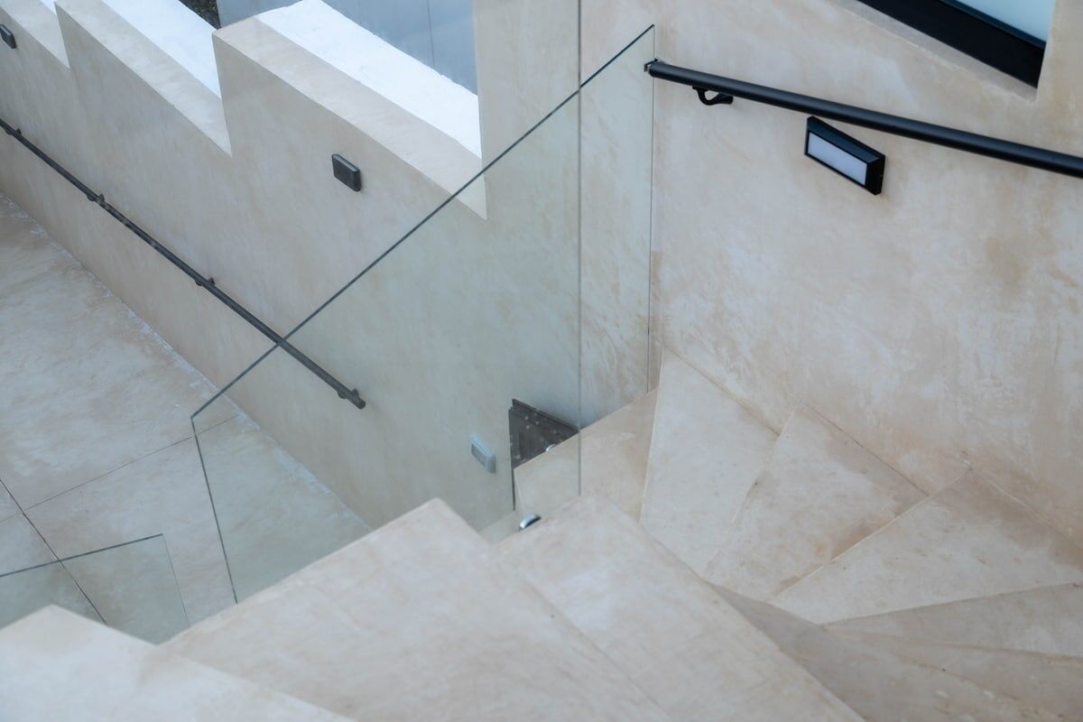Eine moderne Treppe mit Glastrennwand und beigen Wänden.