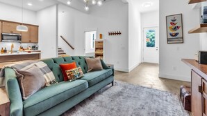 A modern living room with a green sofa, a kitchen in the background, and a staircase leading to another level. - Three bedroom  in United States of America, Spartanburg (Spartanburg)