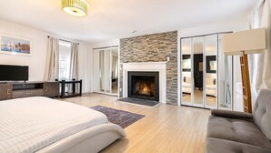 Une chambre moderne avec une cheminée, un lit, un canapé et un téléviseur.