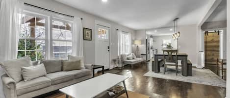 A spacious living room with a sofa, coffee table, and dining area.