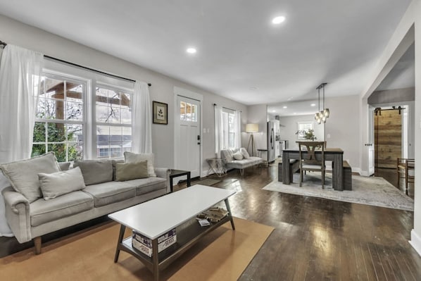 A spacious living room with a sofa, coffee table, and dining area.