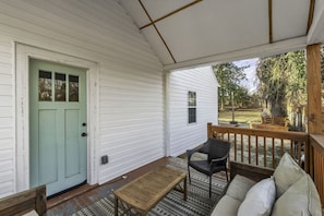 A covered porch with a wooden bench, a chair, and a sofa.