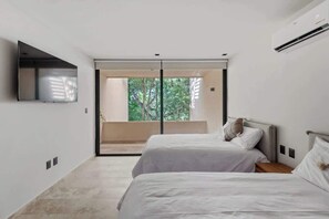 Camera da letto moderna con due letti, una TV e una porta scorrevole in vetro che dà su un balcone.