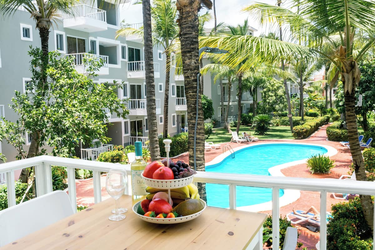 A balcony with a fruit bowl, a glass, and a bottle of wine.