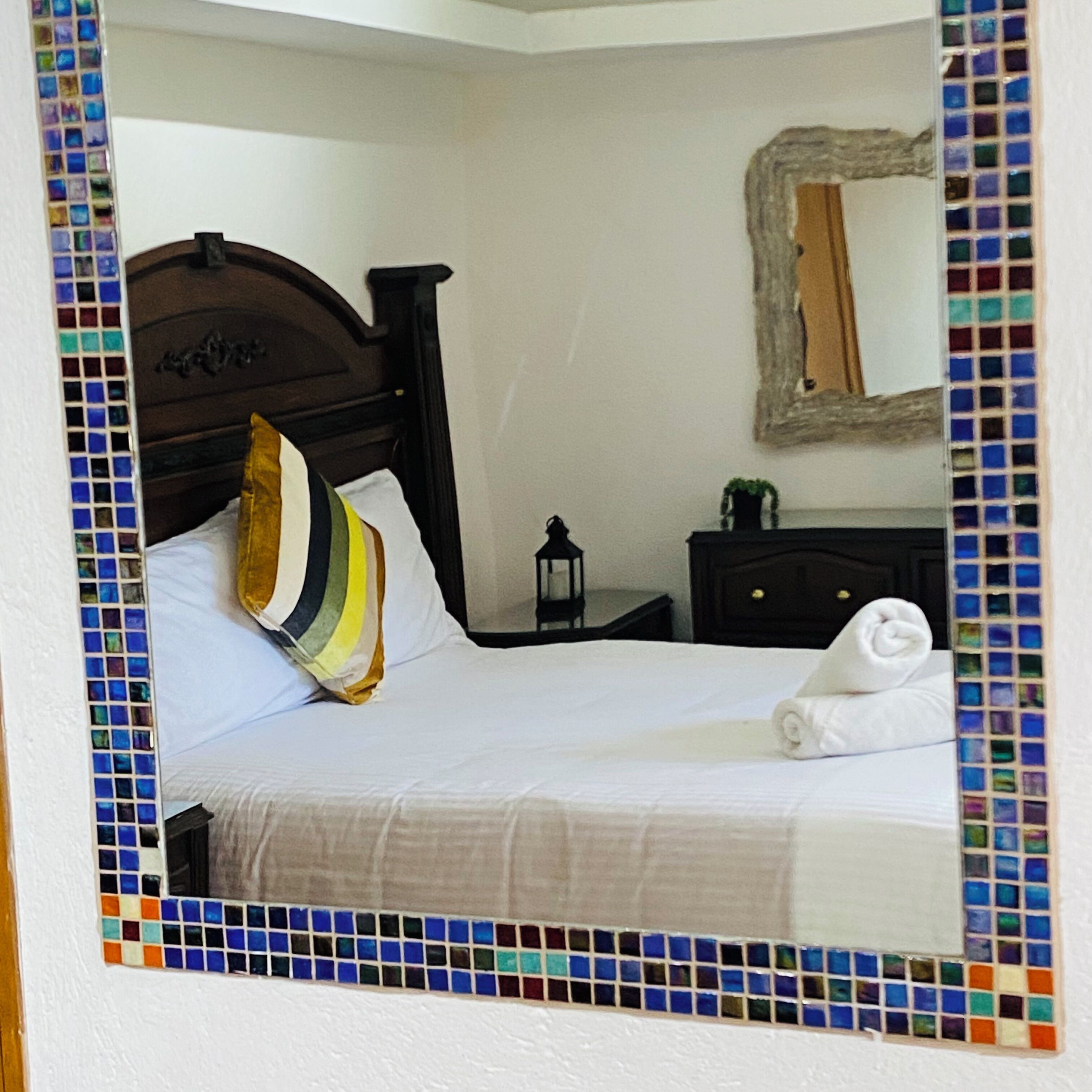 A neatly made bed with white linens, a wooden headboard, and a striped pillow.