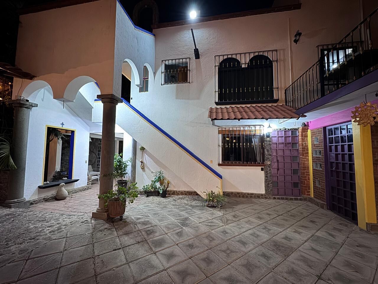 A courtyard with a tiled floor, a staircase, and a building with a balcony.