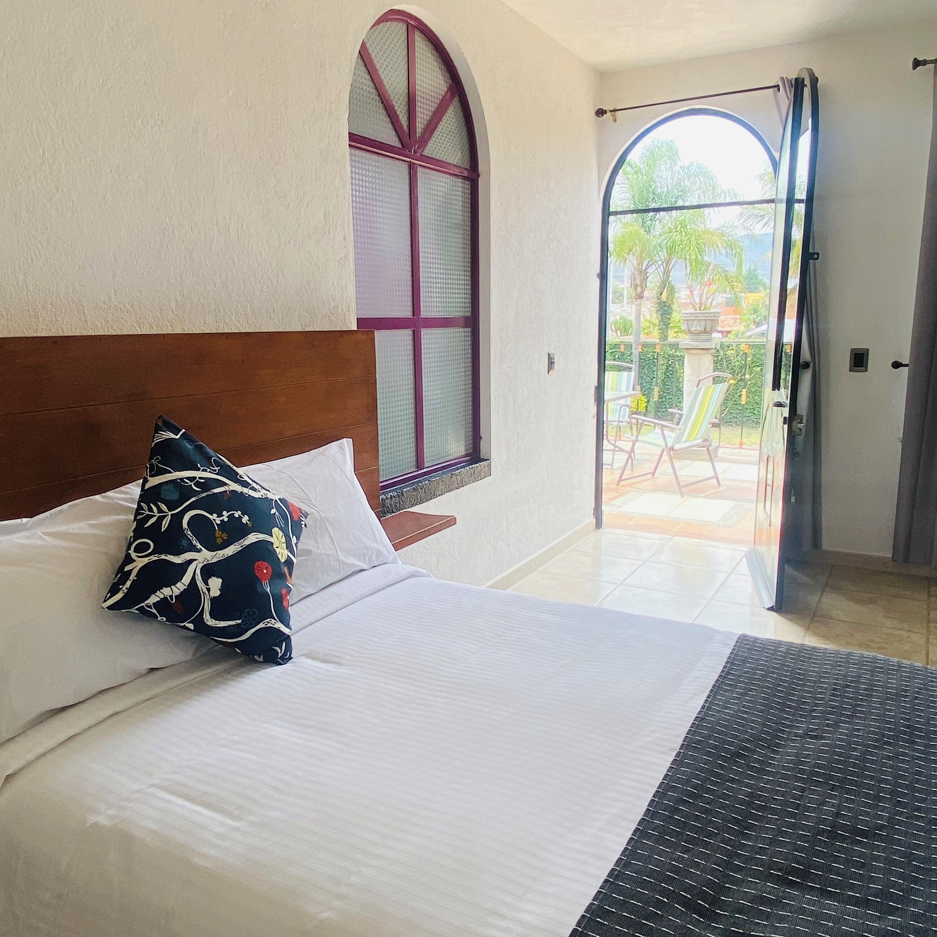 Une chambre d’hôtel avec un lit, une fenêtre donnant sur l’extérieur et une porte menant à un balcon.