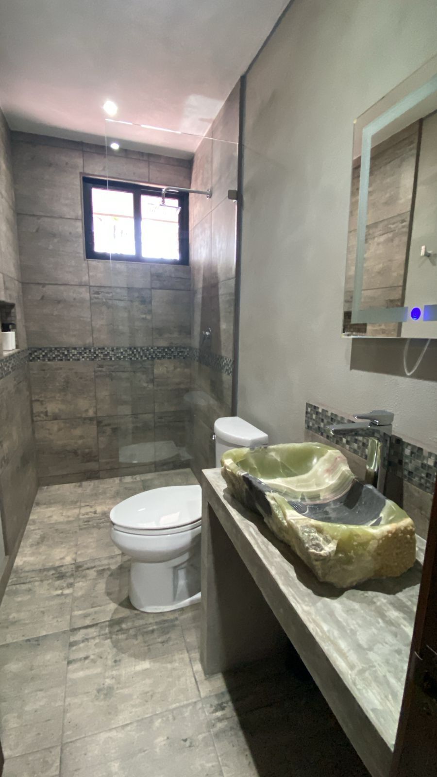 Ein Badezimmer mit Toilette, einem Waschbecken mit ungewöhnlicher Formgebung und einer Duschkabine.