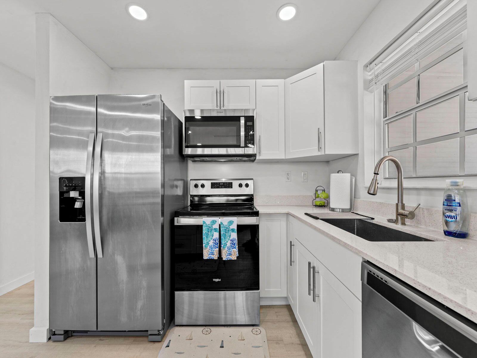 A modern kitchen with stainless steel appliances, white cabinetry, and a built-in oven.