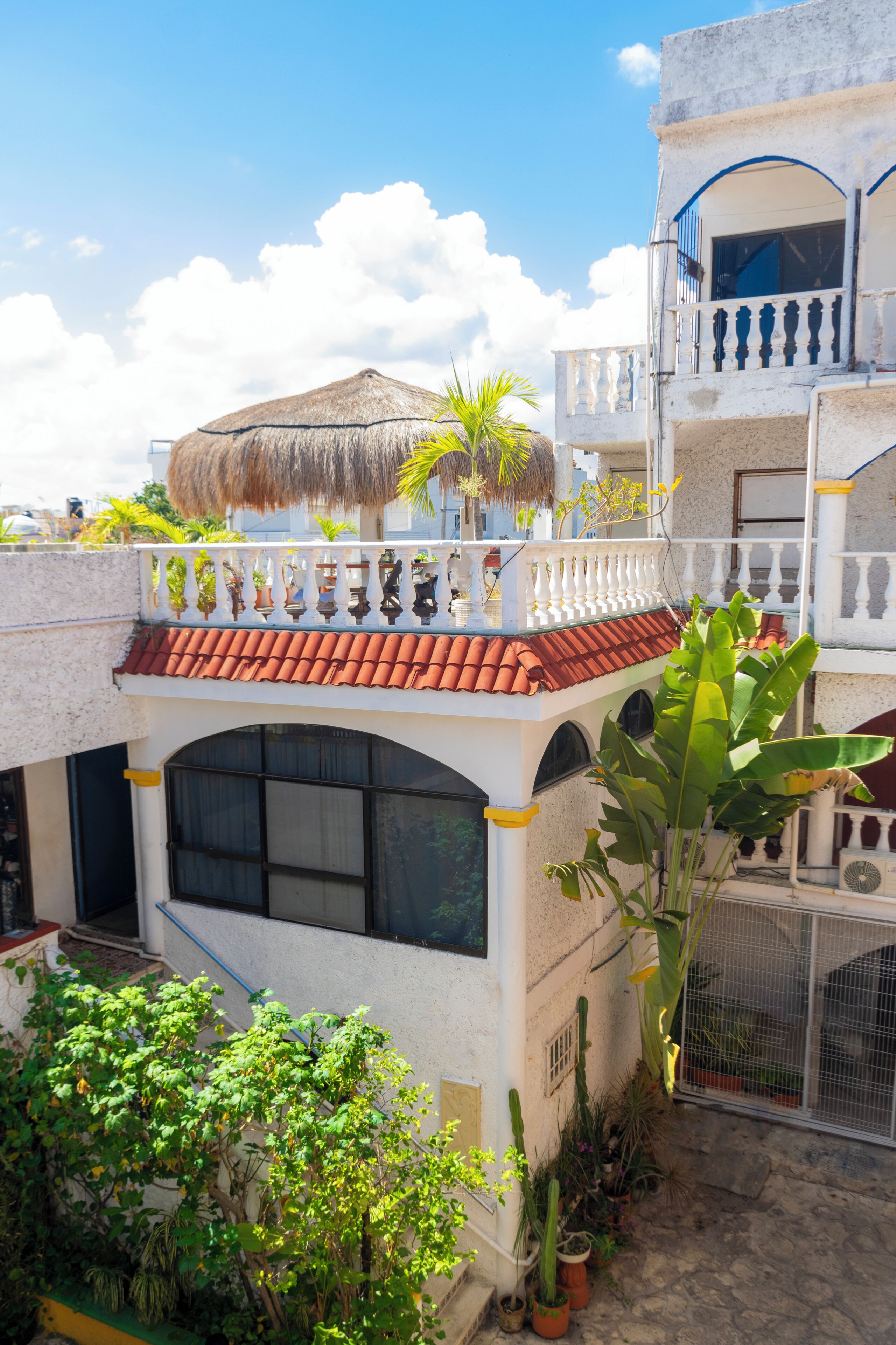 Un immeuble à plusieurs étages, doté d’un toit recouvert de tuiles rouges, de balcons et de plantes en pot.