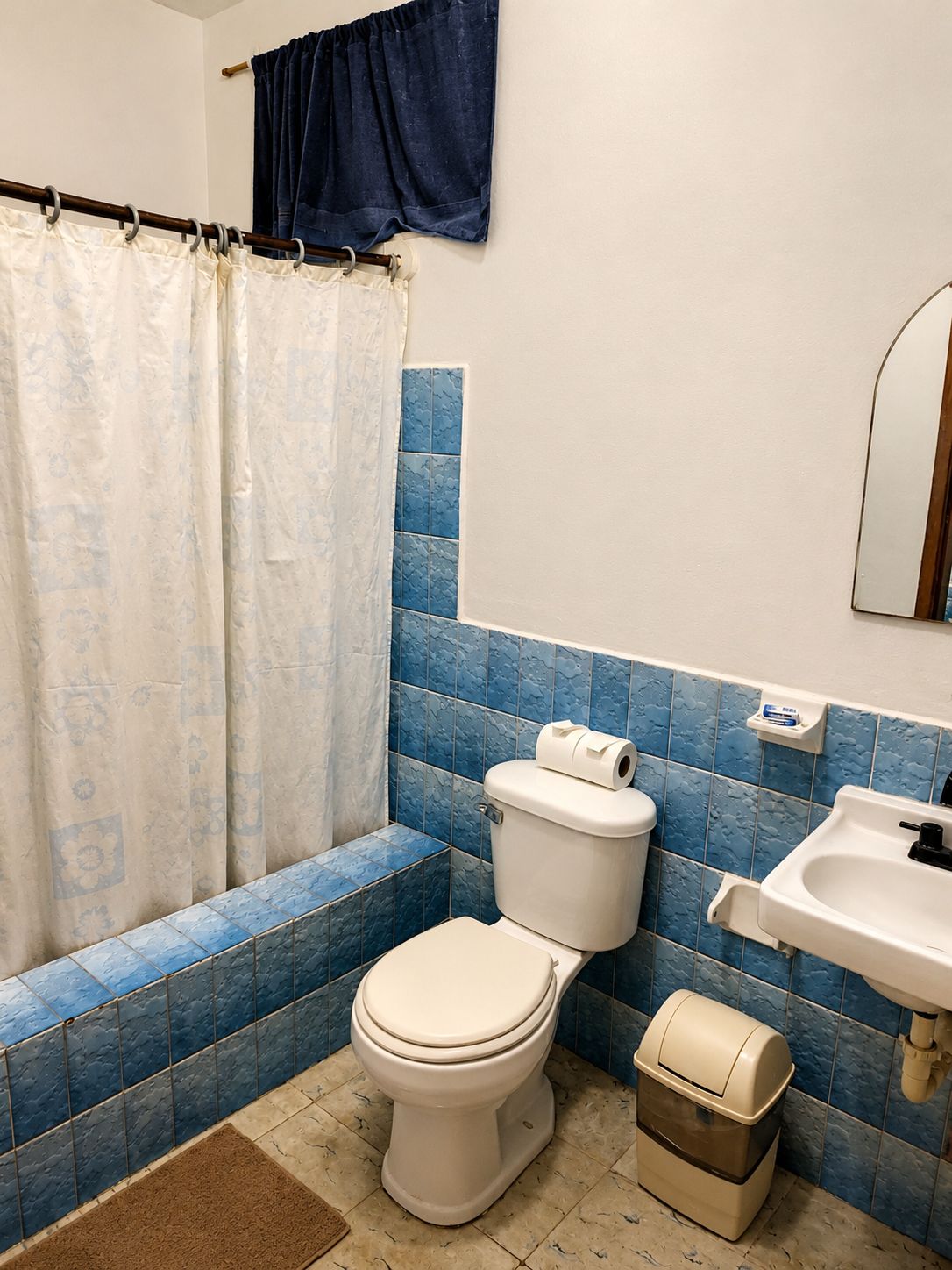 A bathroom with a toilet, sink, and blue-tiled walls.