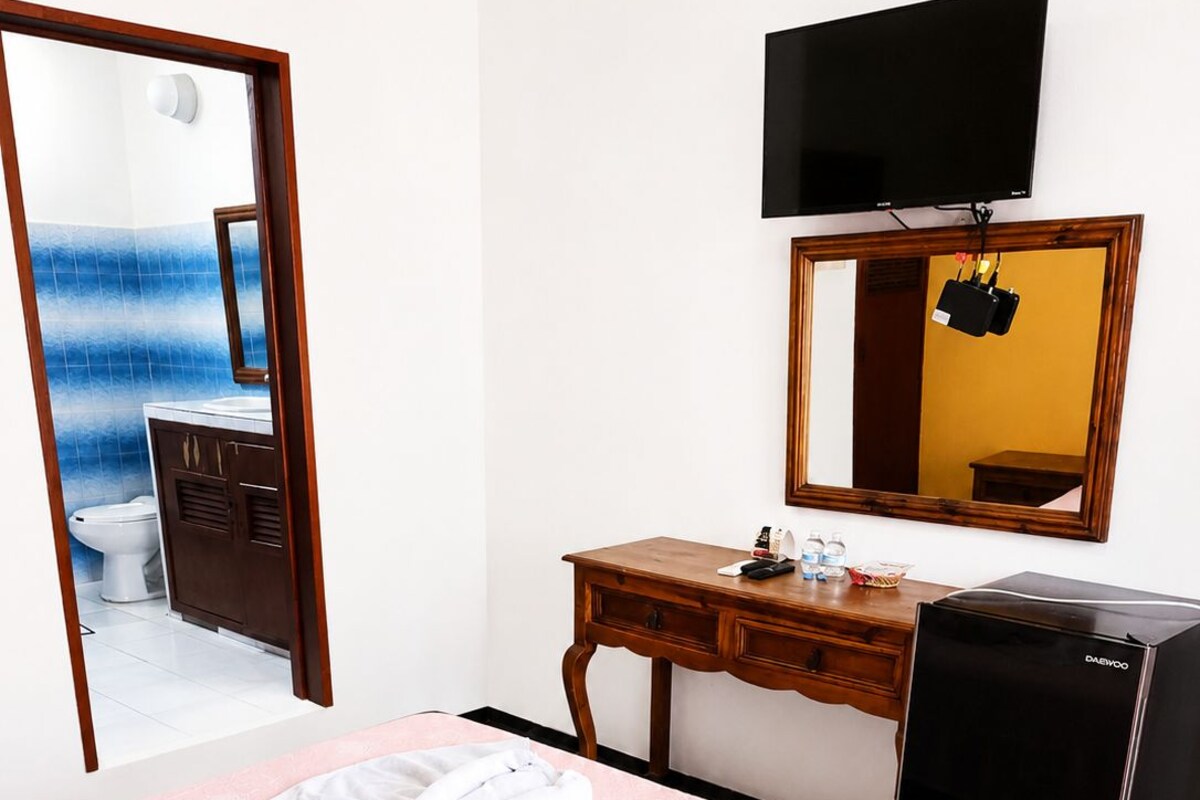 Ein Hotelzimmer mit Bett, Schreibtisch, Fernseher und Spiegel.