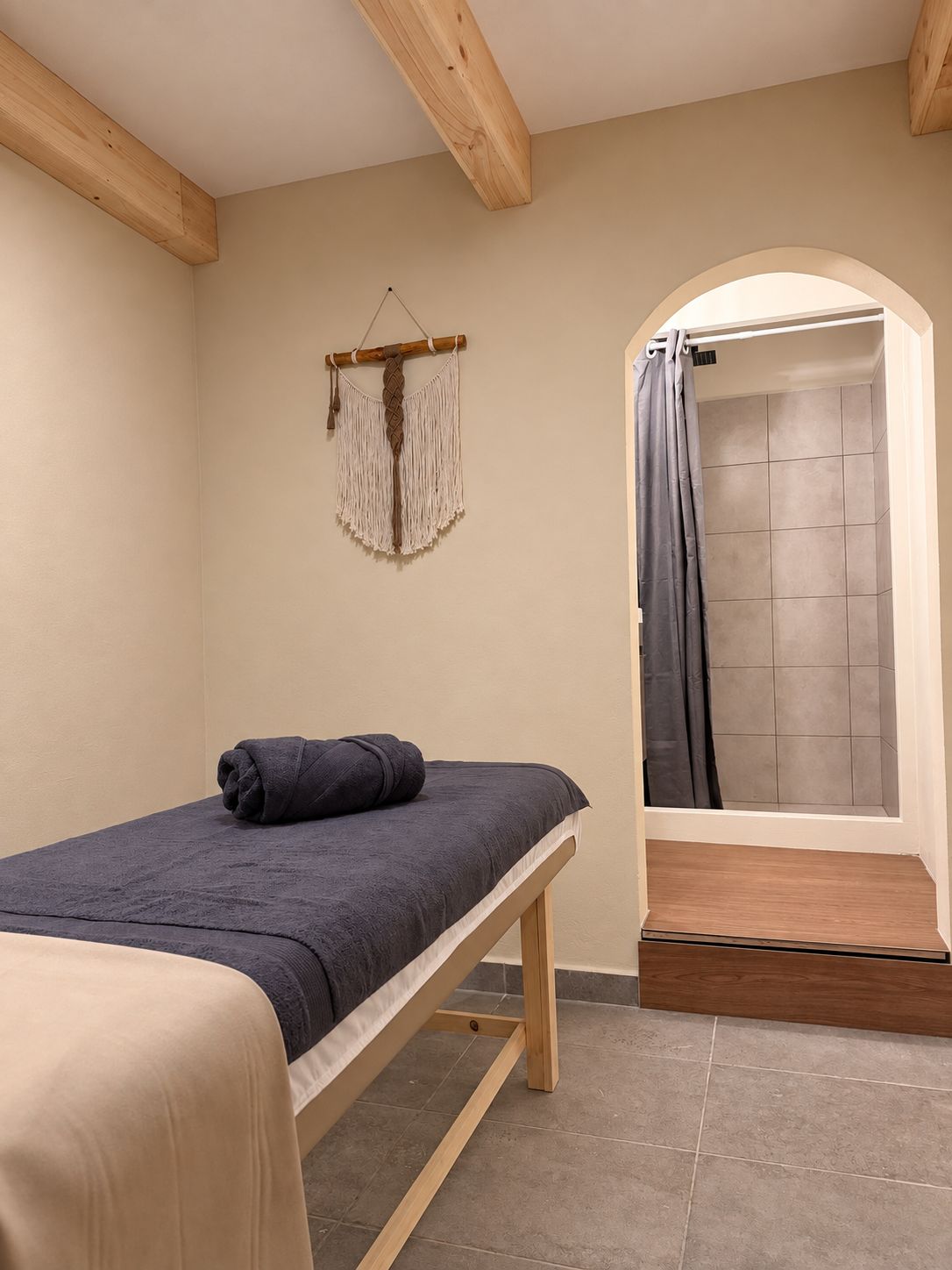 Una habitación pequeña y sencilla con cama, ducha y un tapiz de macramé.