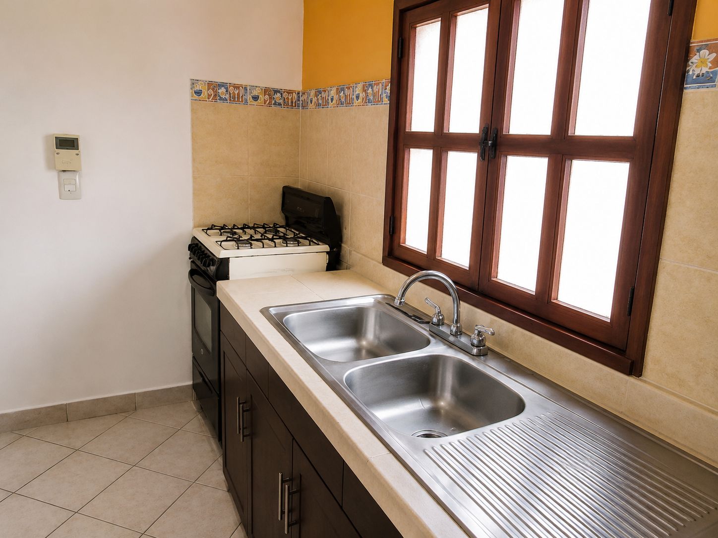 A kitchen with a double sink, a stove, and a window with a view.