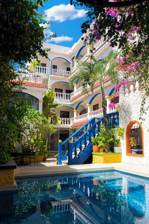A pool area with a blue staircase, multiple balconies, and lush greenery.