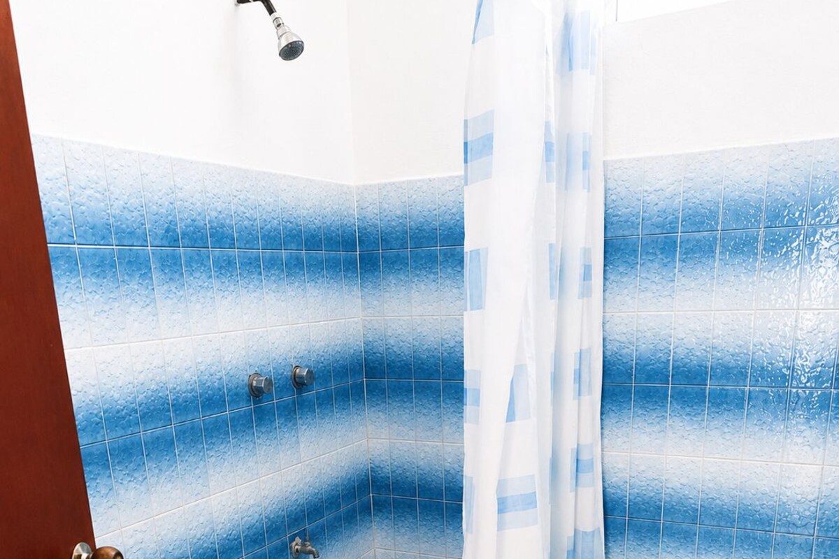 Un baño con una bañera jacuzzi con azulejos azules, una ducha y un perchero.