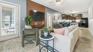 A modern living room with a sofa, chairs, a TV, and a small table with a plant. - Spacious Modern 2BR 2Bath | Free Parking | Near City Center (Indianapolis)