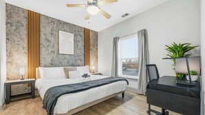 A modern bedroom with a bed, desk, and ceiling fan. - Spacious Modern 2BR | Free Parking | Near City Center (Indianapolis)