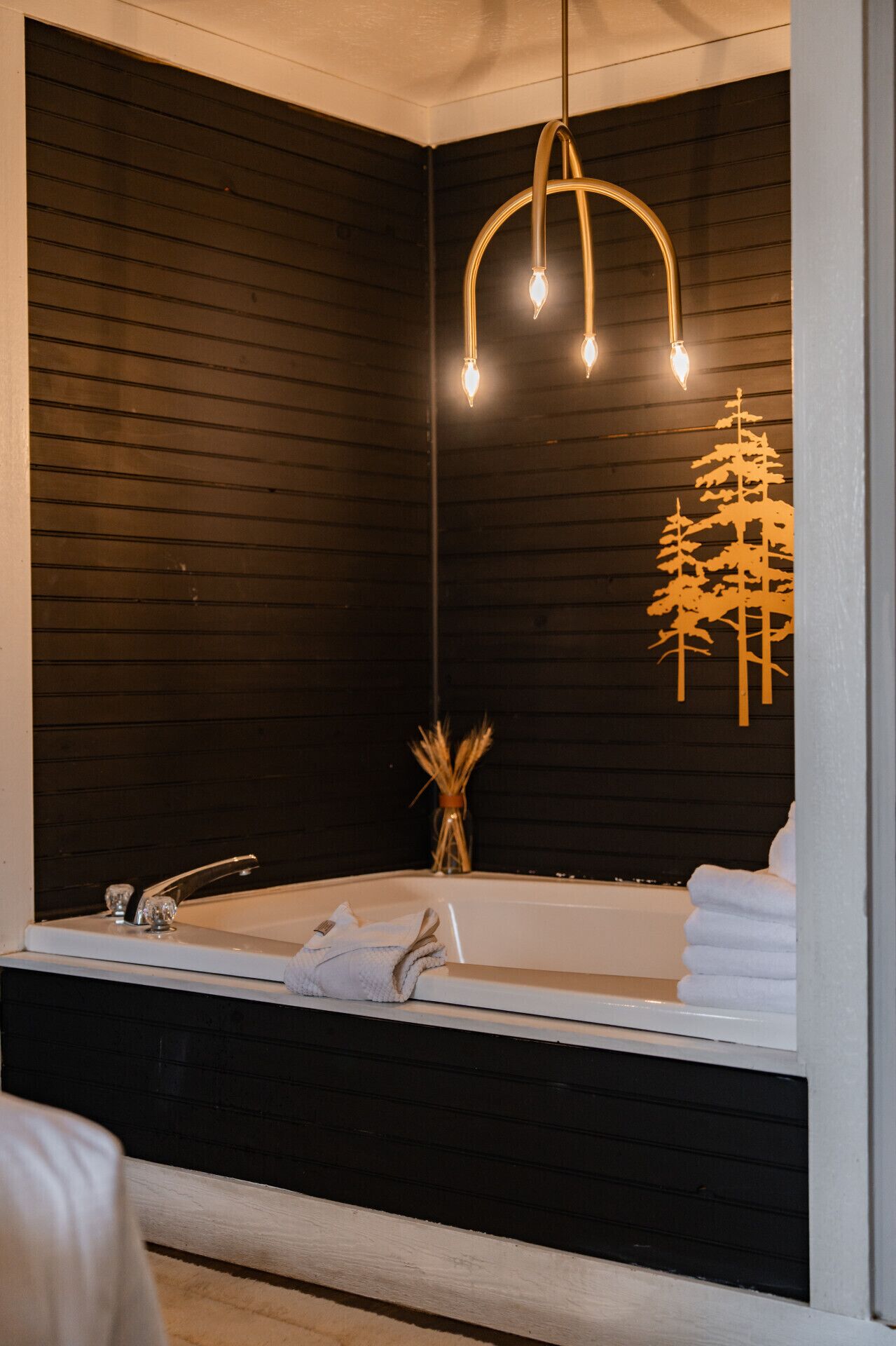 Un baño moderno con una bañera grande, una pared de madera y una lámpara colgante.