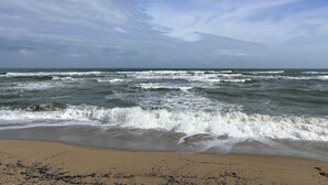 Une plage où les vagues se brisent sur le rivage sous un ciel nuageux.