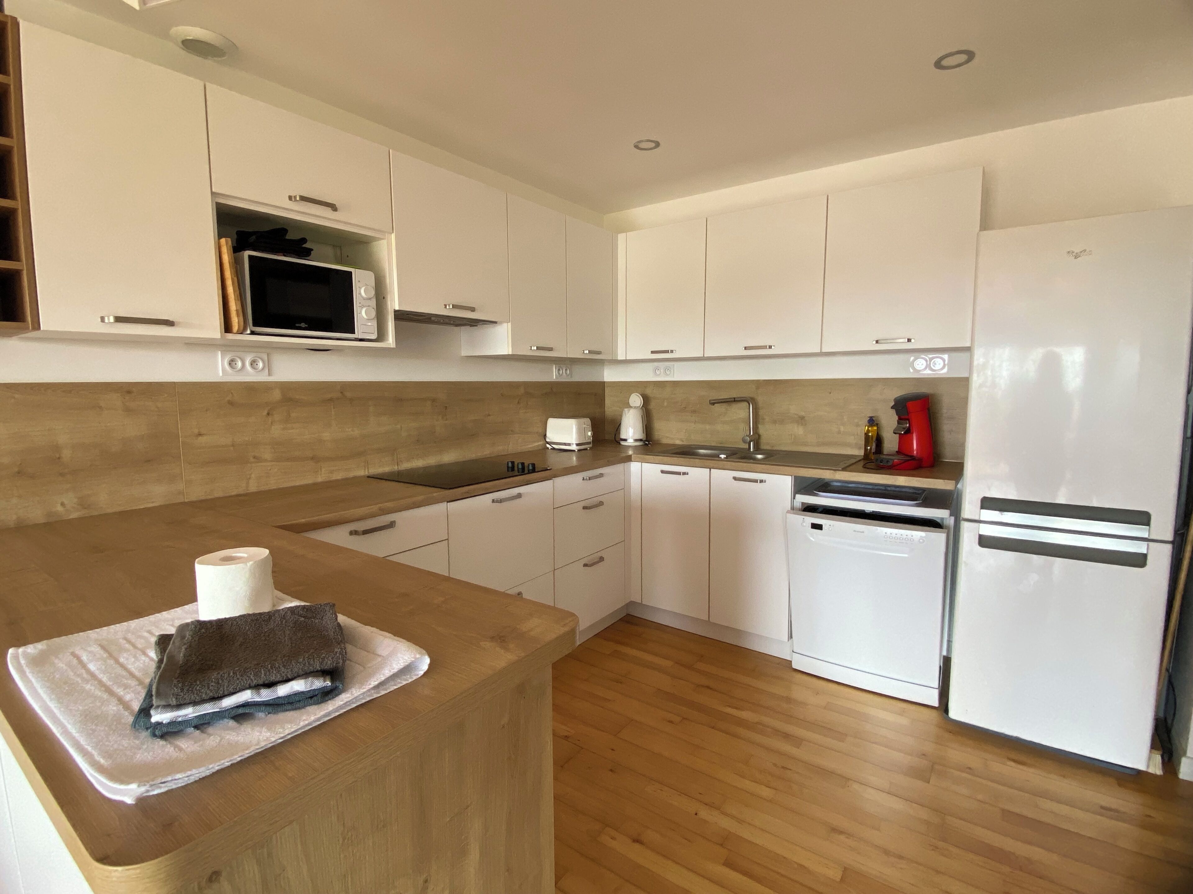 A modern kitchen with white cabinets, a wooden countertop, a microwave, a toaster, and a dishwasher.