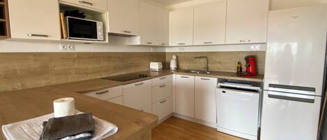 A modern kitchen with white cabinets, a wooden countertop, a microwave, a toaster, and a dishwasher.