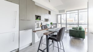Een moderne keuken met witte kastjes, een eethoek met een tafel en stoelen, en een groene bank.