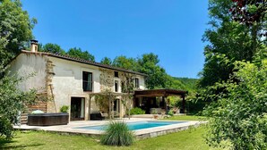 A rustic stone house with a swimming pool, surrounded by lush greenery and a clear blue sky. - Luxueuse maison de campagne isolée, nichée dans la forêt au milieu des oiseaux. (Lesparrou)