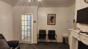 A living room with a fireplace, two black chairs, a couch, and a door with frosted glass panels. - Come and Enjoy My Peaceful Home, Your Comfort Zone (Manchester)