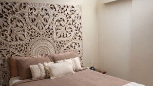 A bedroom with a large bed, a decorative headboard, and a nightstand with a lamp. - Taman Sari Luxury Private Pavilions (Mapleton)