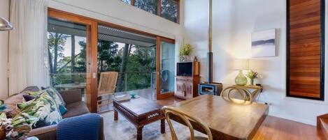Een ruime kamer met een grote houten eettafel, een comfortabele bank en een balkon met glazen deuren.