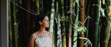 A person sitting on a wooden bench in a bamboo forest.